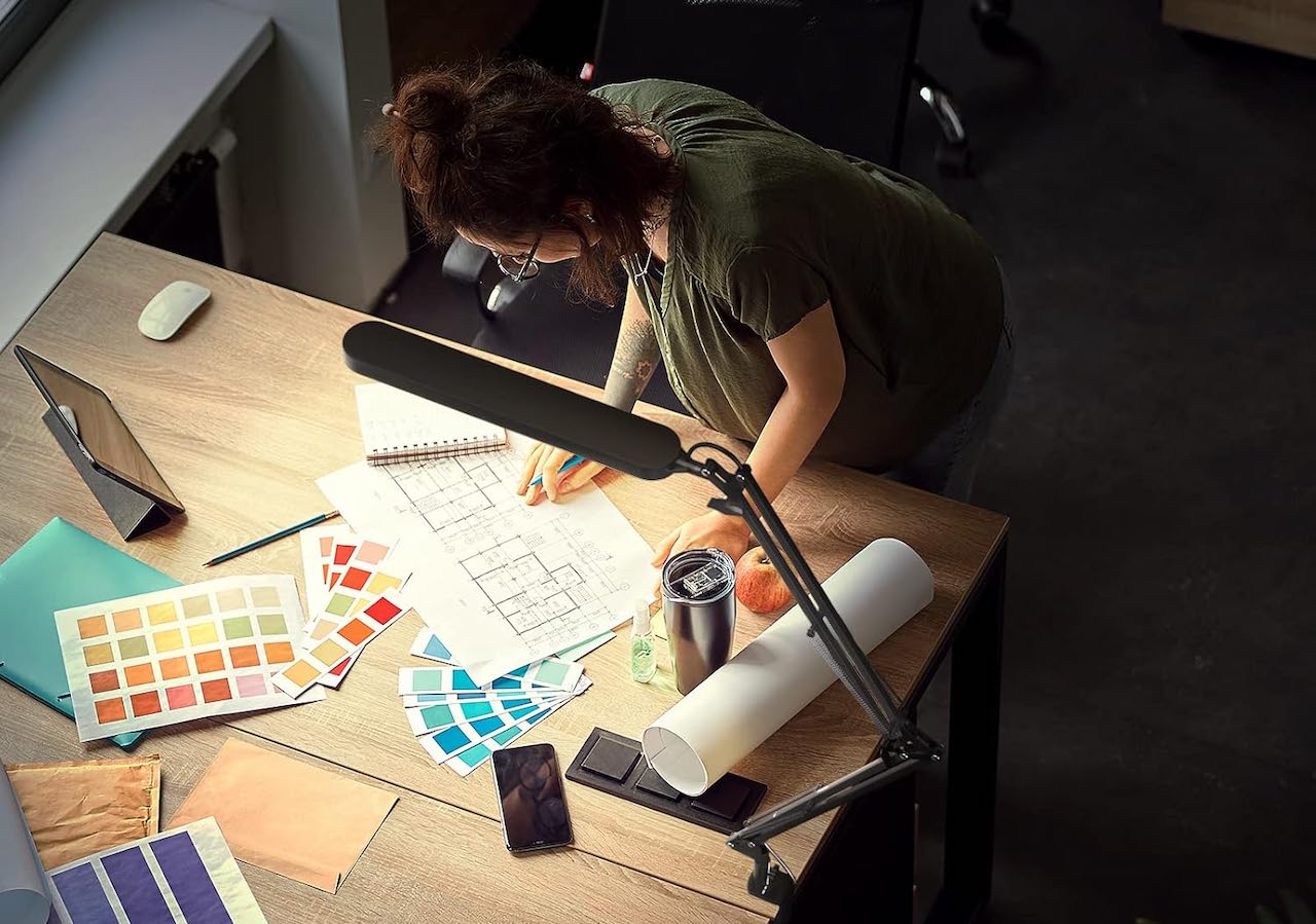 Une femme qui travaille sur un bureau avec une lampe de bureau.