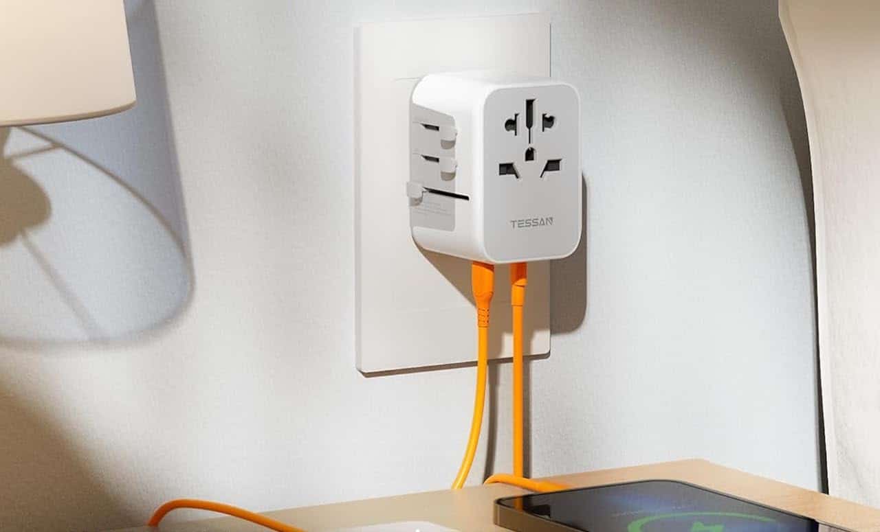Un adaptateur universel sur un prise au dessus d'une table de chevet.