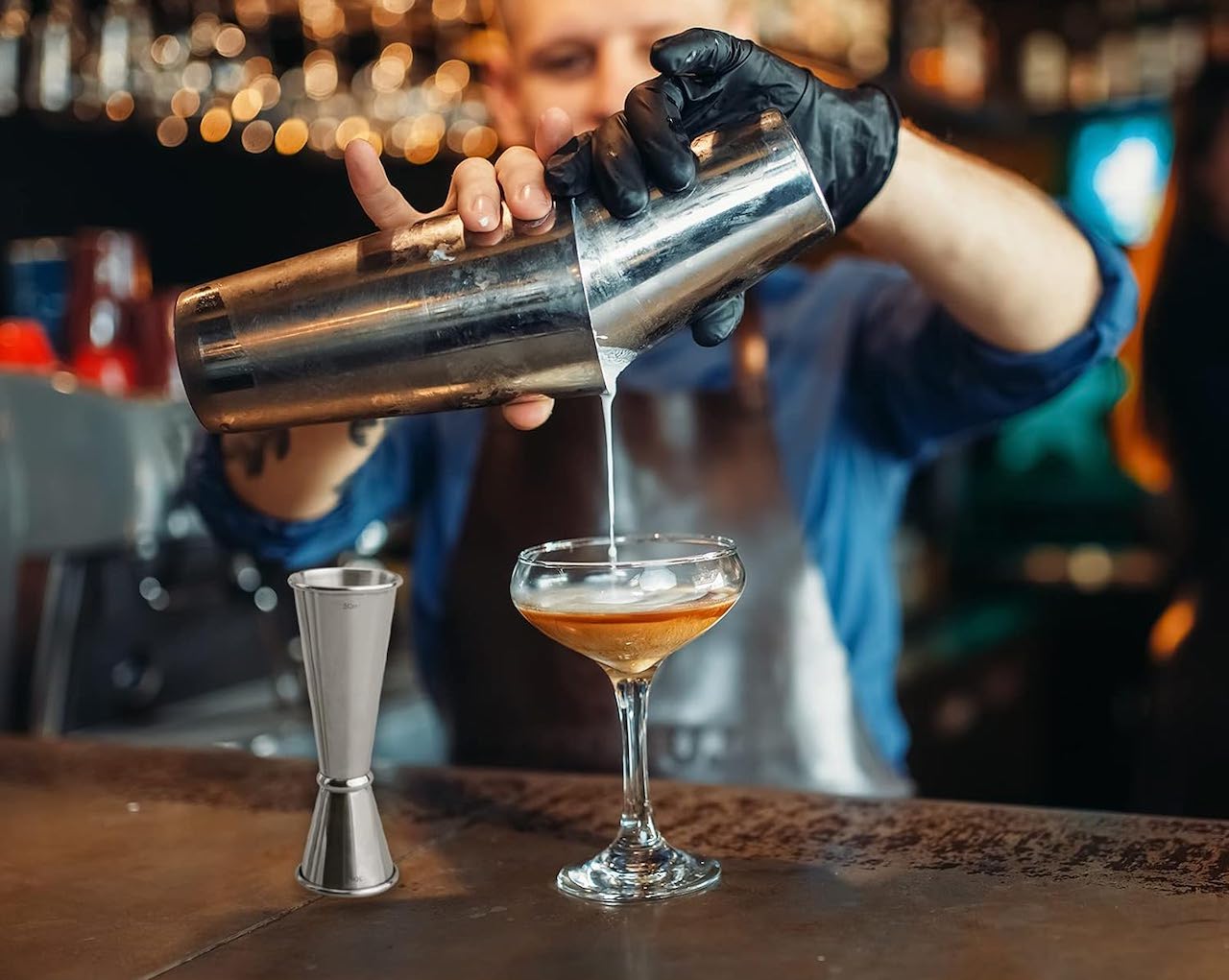 Un homme qui verse un cocktail depuis un shaker à cocktail.