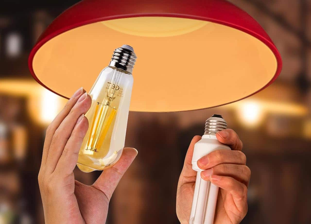 Une personne qui remplace une ampoule par une ampoule connectée sur une lampe.