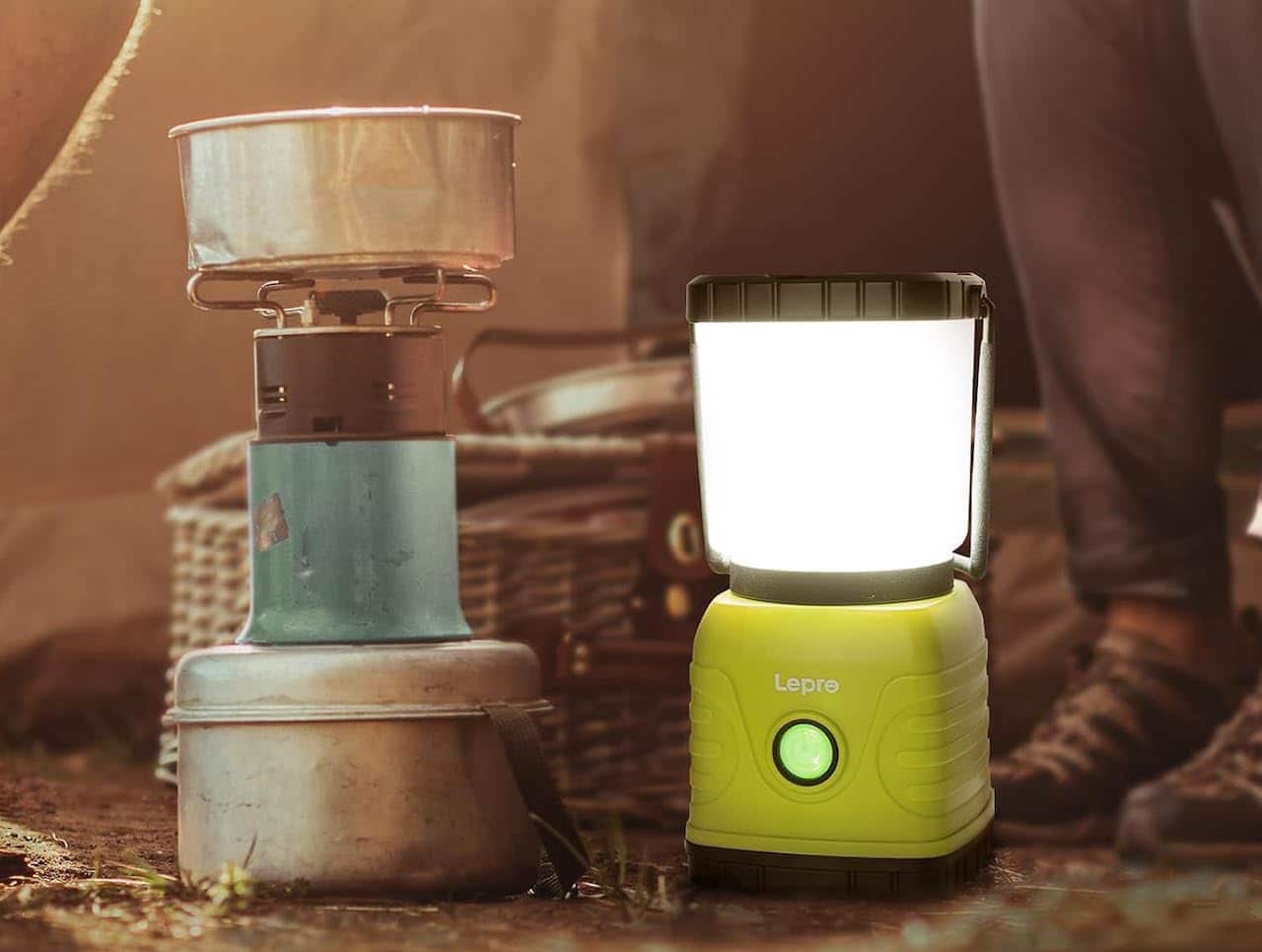 Une lampe de camping posée par terre près d'une casserole de camping.