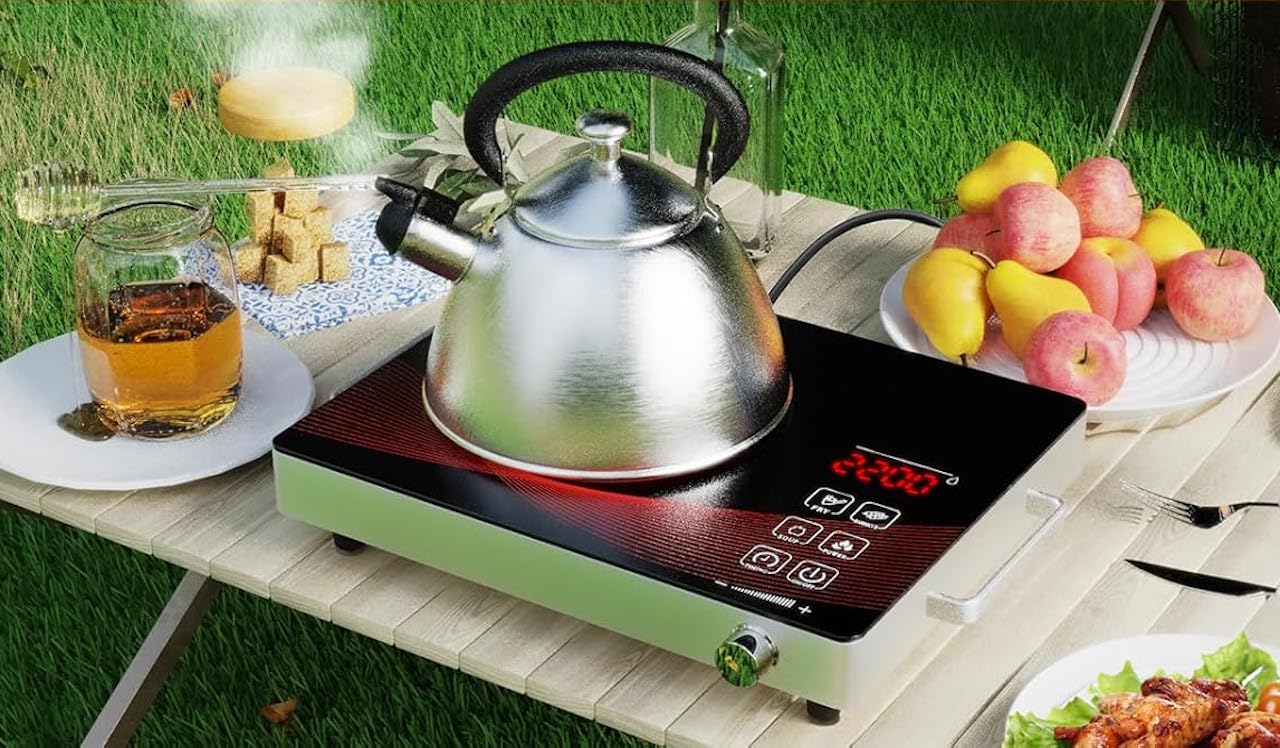 Une théière posée sur un réchaud à induction sur une table de jardin.