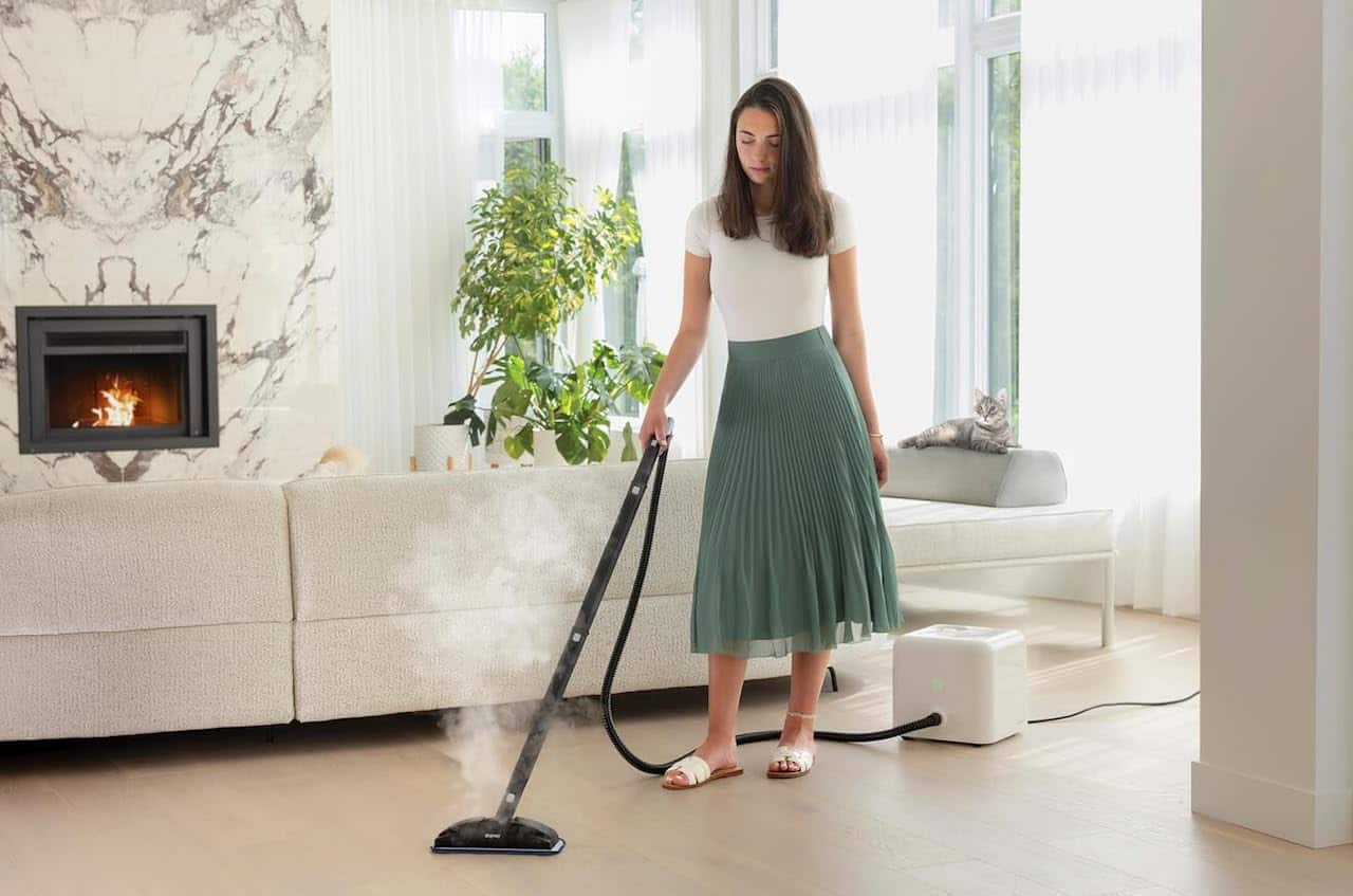 Une femme qui utilise un nettoyeur vapeur sur le parquet de son salon.