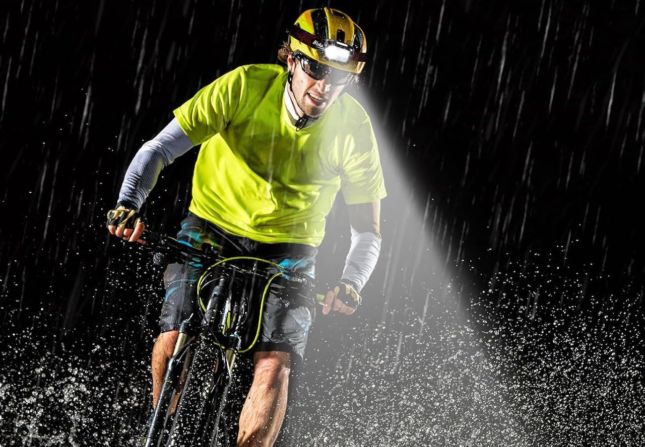 Un homme qui fait du vélo la nuit grâce à une lampe frontale.