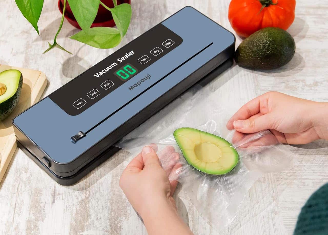 Une femme qui utilise une machine sous vide pour conserver un avocat.