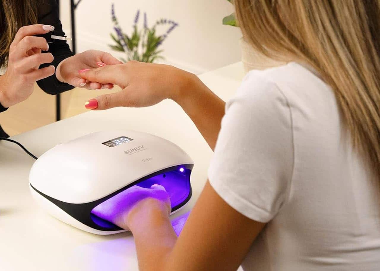 Une femme qui utilise une lampe UV ongle.