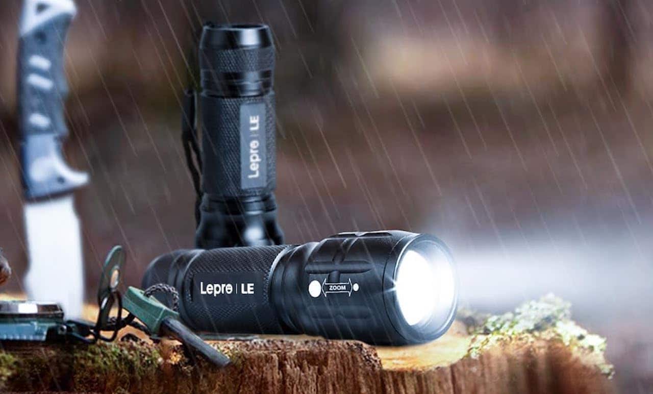 Une lampe torche posée sur du bois dans la nuit sous la pluie.