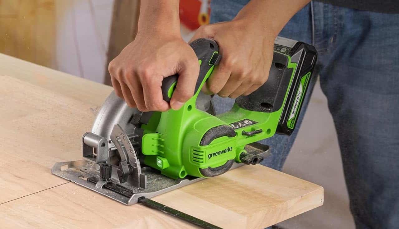 Un homme qui utilise une scie circulaire de la marque Greenworks.