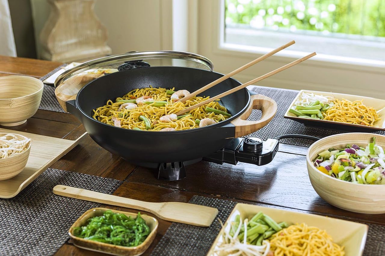 Un wok électrique sur une table à manger.