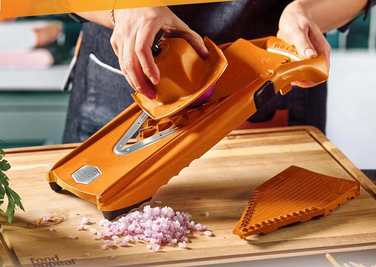 Une personne qui utilise une mandoline de cuisine pour couper des oignons.