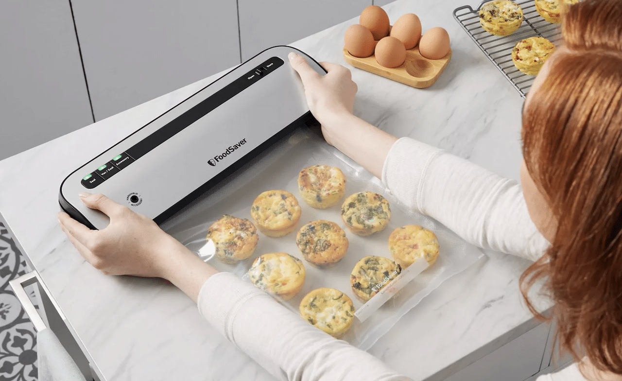 Une femme qui utulise une machine sous vide pour conserver de la nourriture.