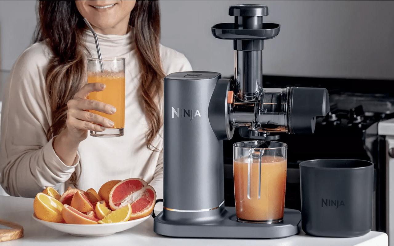 Une femme qui prépare un jus à l'aide d'un extracteur de jus.