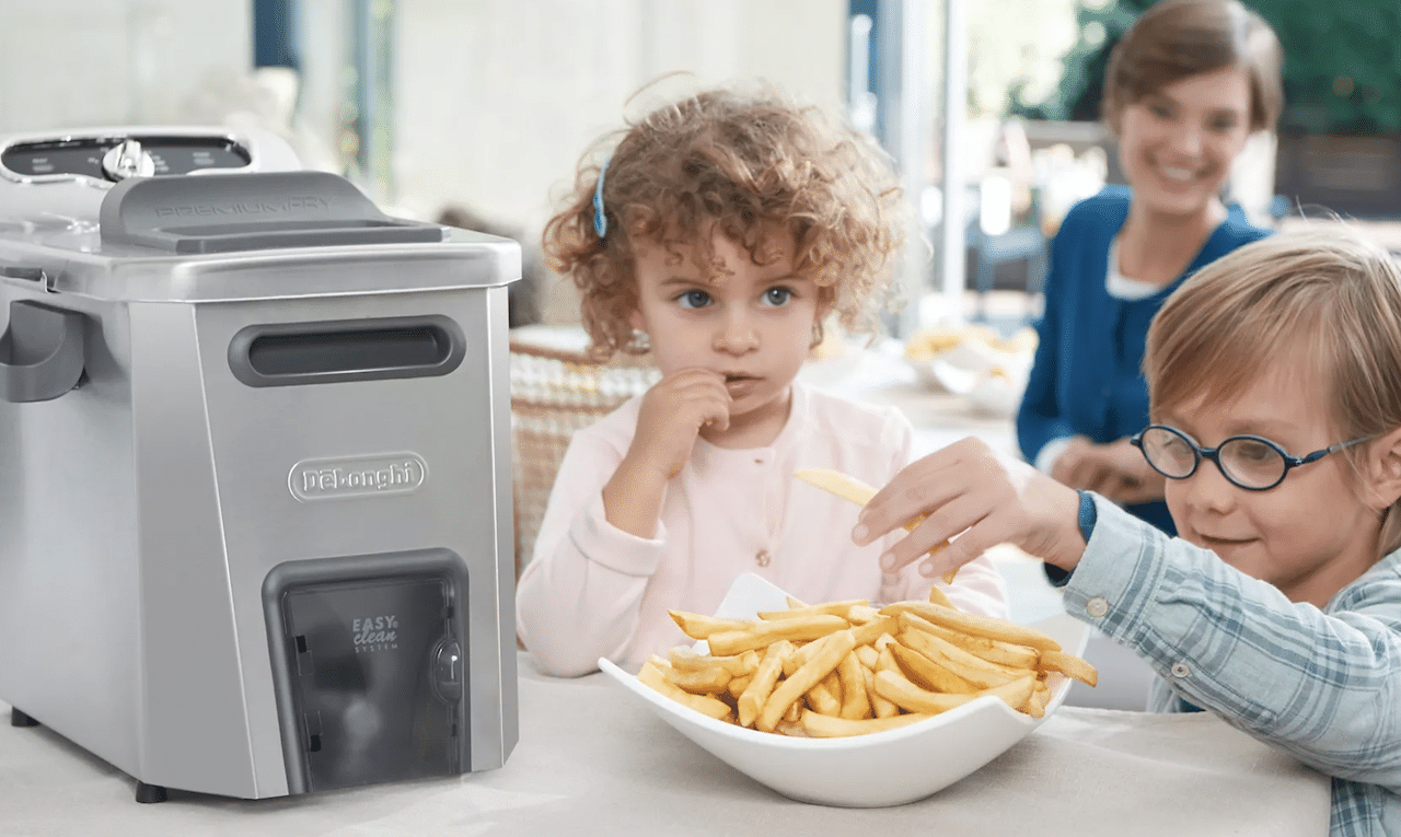 Des enfants qui mangent des frites préparés avec une friteuse avec huile.