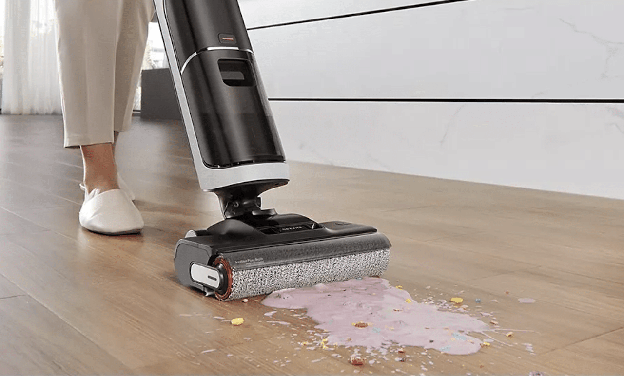 Une femme qui utilise un aspirateur sans fil dans sa cuisine.