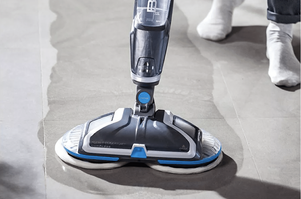 Un homme qui utilise une cireuse électrique sur le sol de son salon.