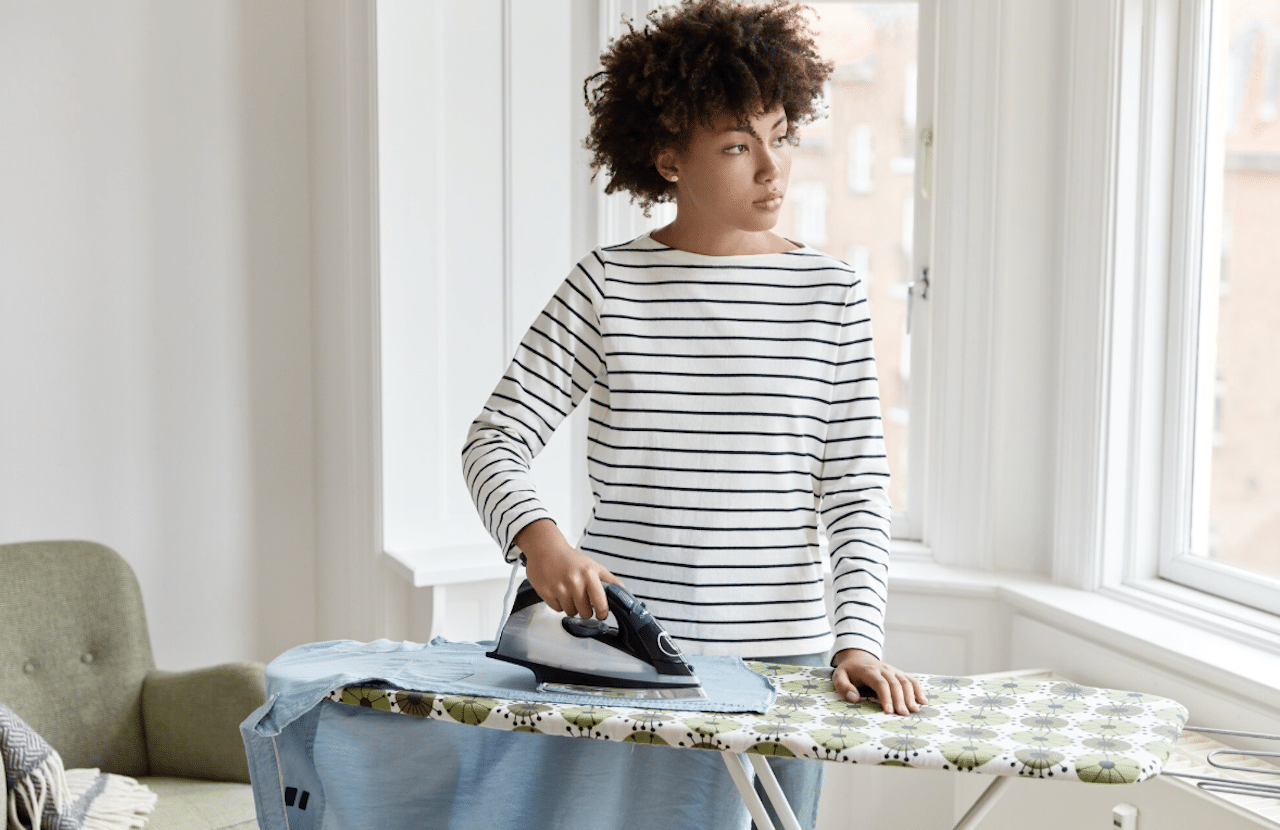 Une femme qui fait du repassage sur une table à repasser.