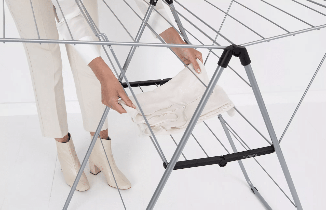 Une femme qui étend son linge sur un séchoir à linge.