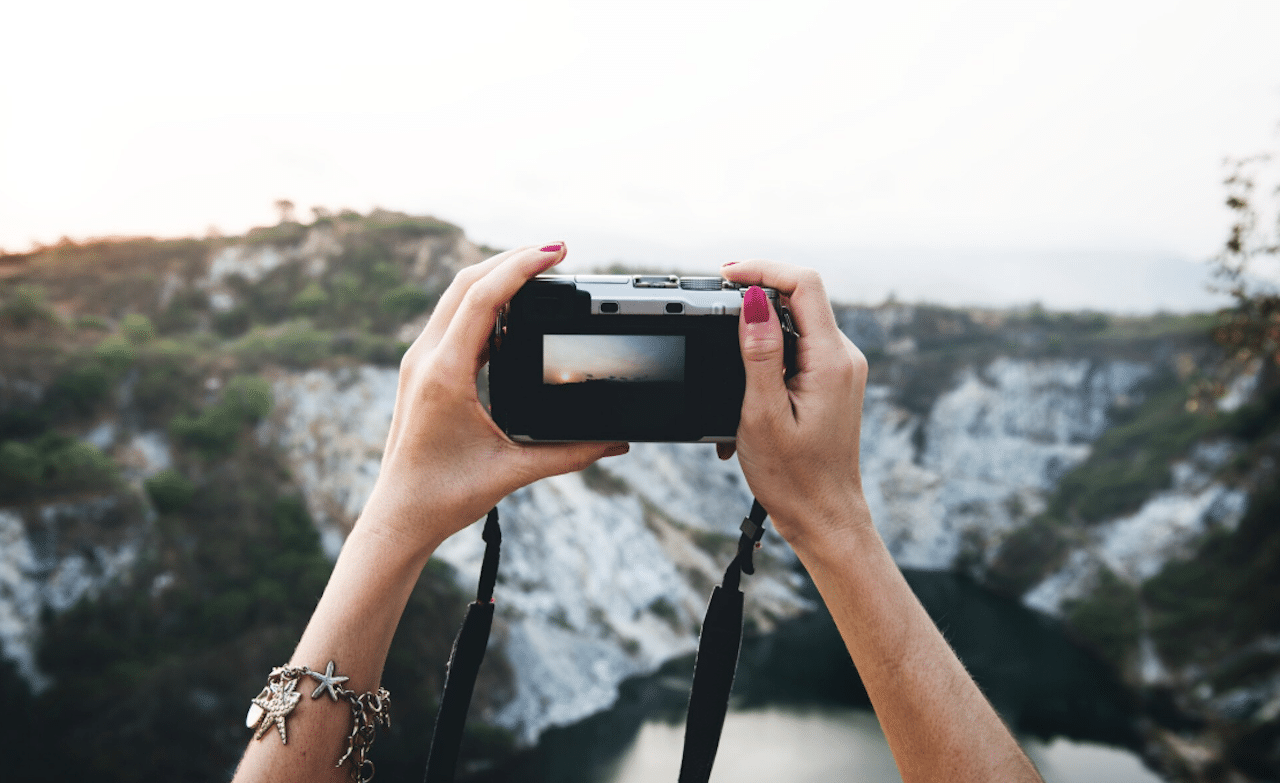 Une femme qui utilise un appareil photo bridge pour capturer un beau paysage.