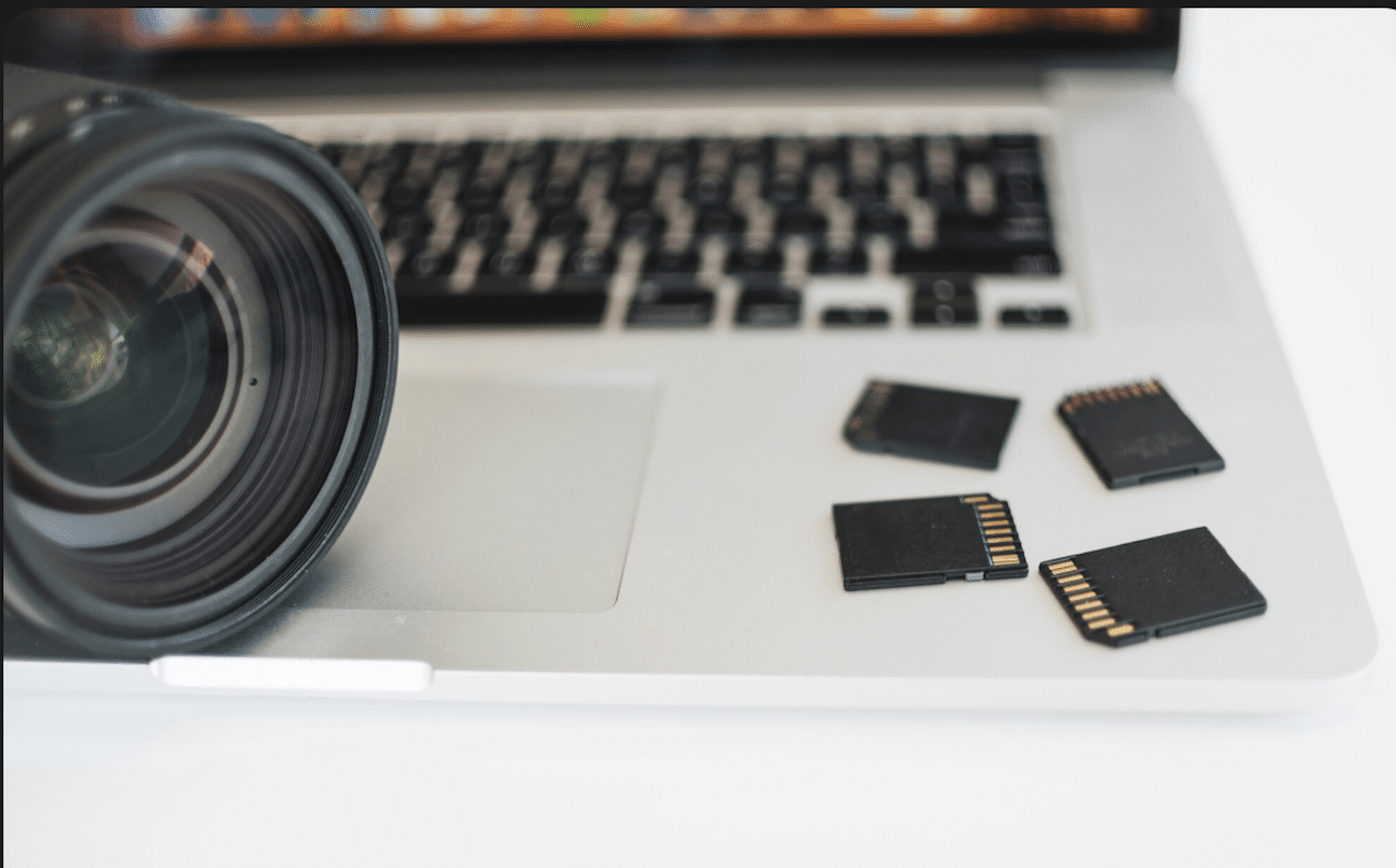 Plusieurs cartes mémoires sur un ordinateur à côté d'un appareil photo.