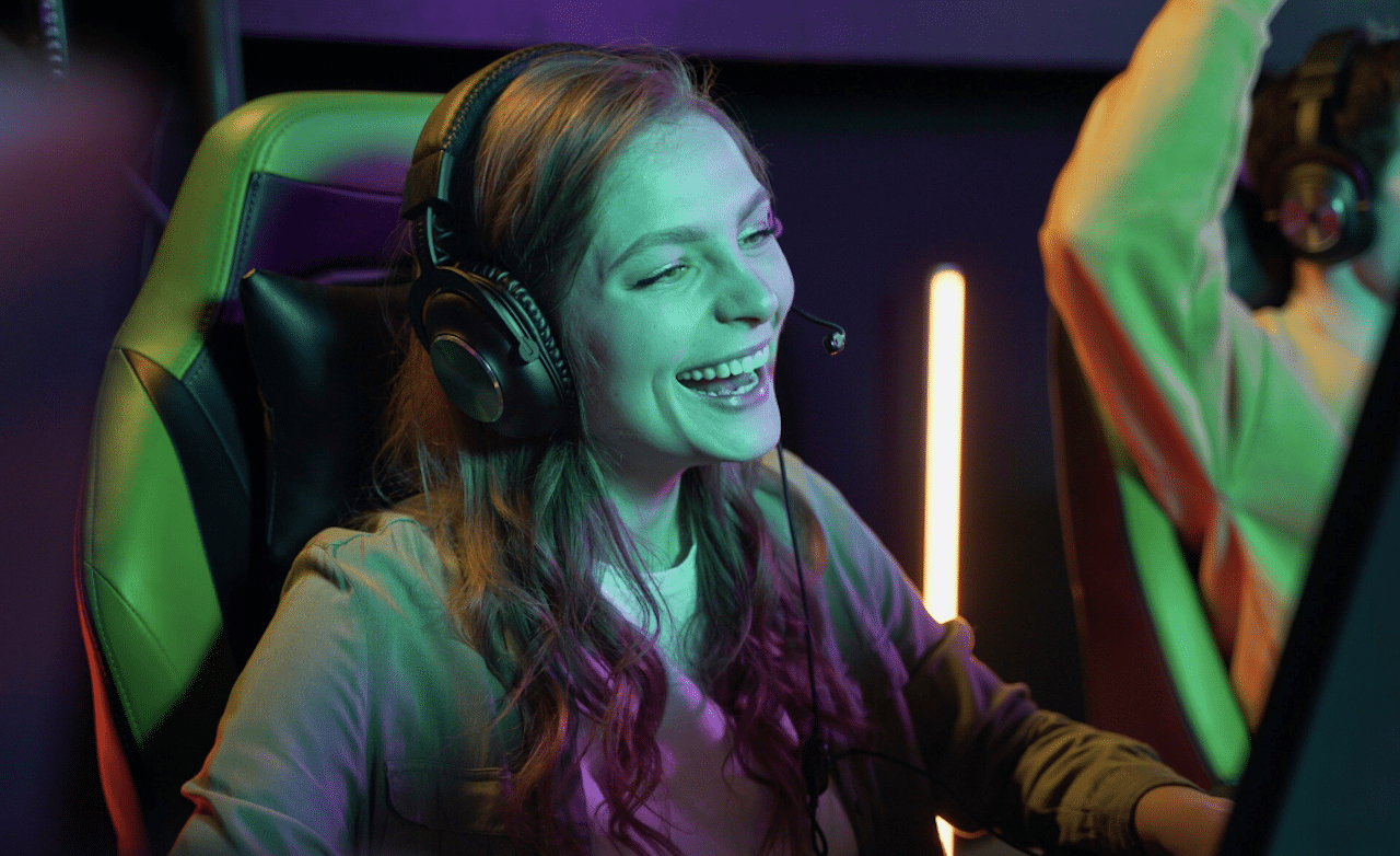 Une femme qui porte un casque gamer pour jouer sur son ordinateur.
