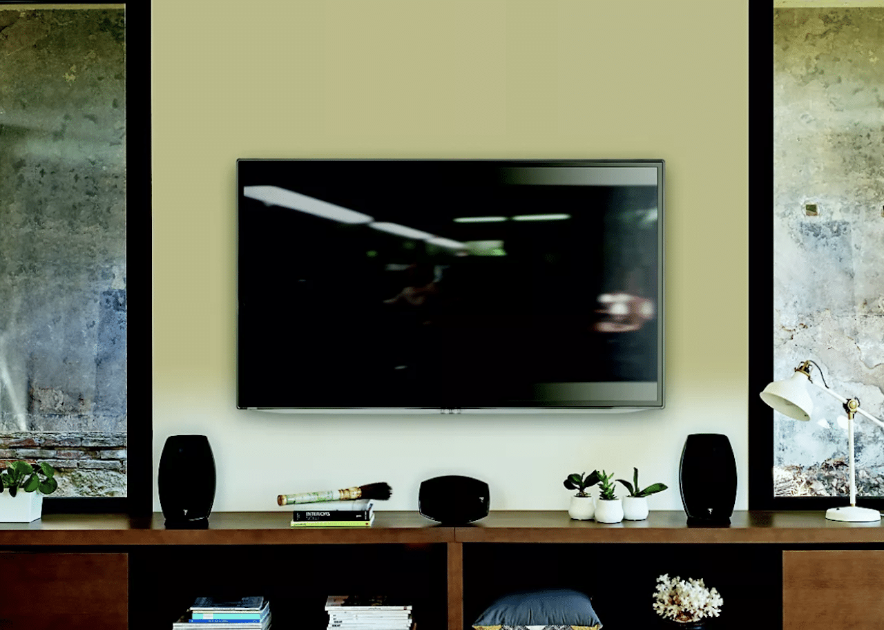 Des enceintes Dolby Atmos près d'un écran plat accroché à un mur de salon.