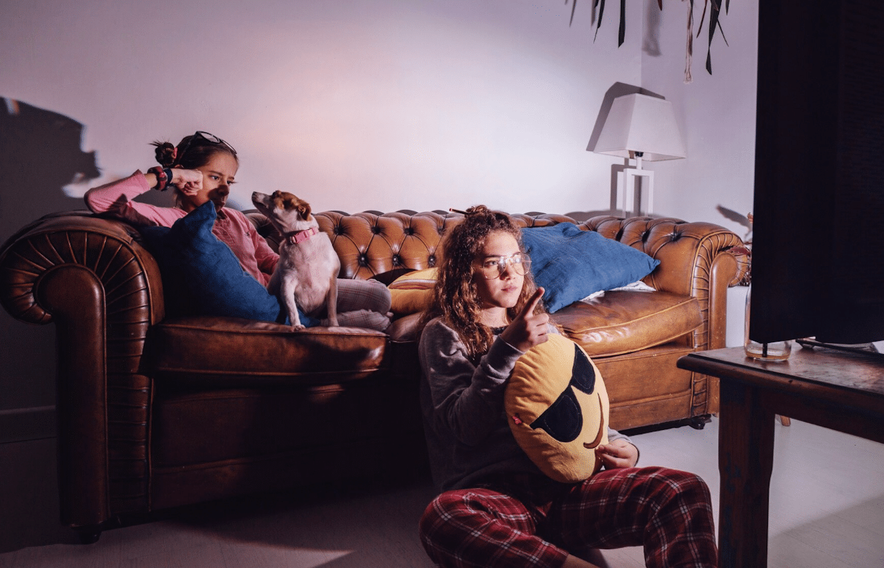 Des enfants sur un canapé qui regardent la télé avec un home cinéma.