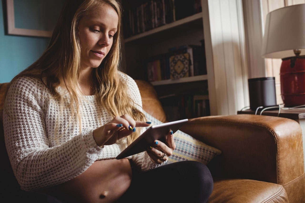 Une femme confortablement assise dans son fauteuil club en cuir utilise une liseuse pour lire un livre