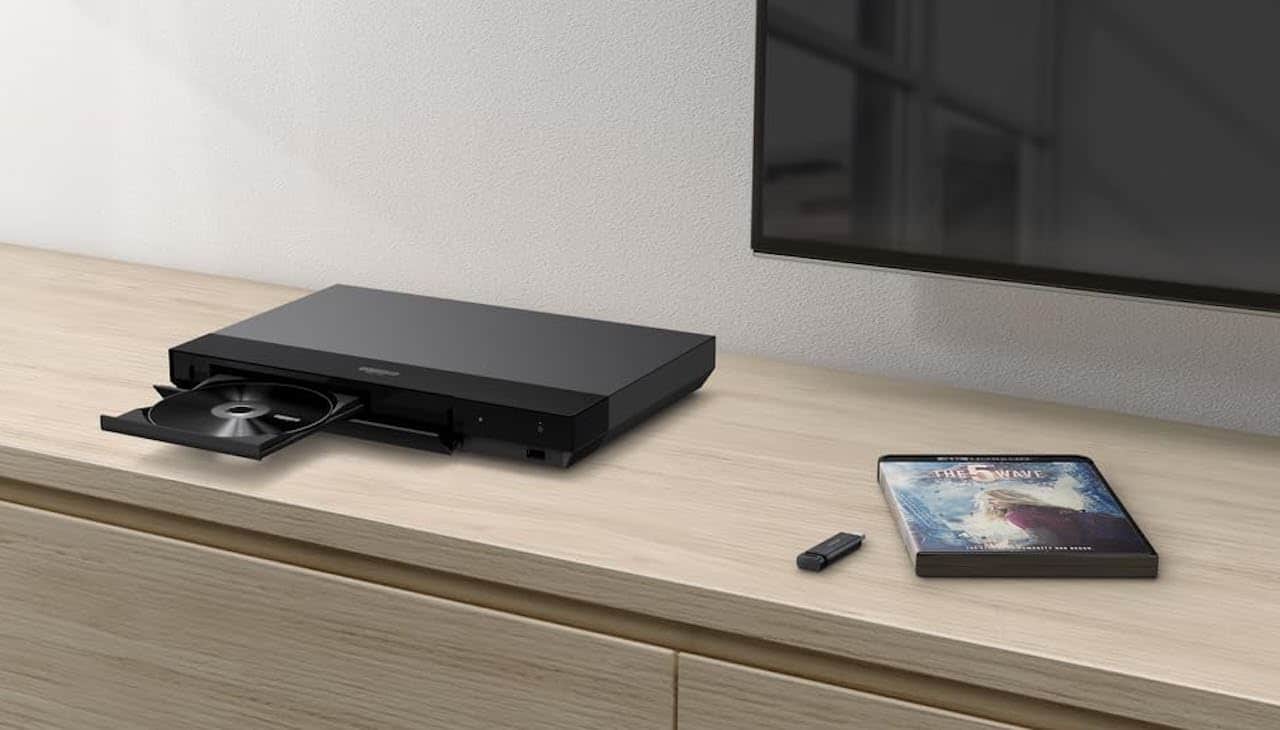 Un lecteur Blu-ray 4K posé sur un meuble TV en bois.