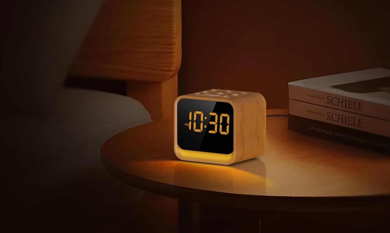 Un radio-réveil posé sur une table de chevet en bois.