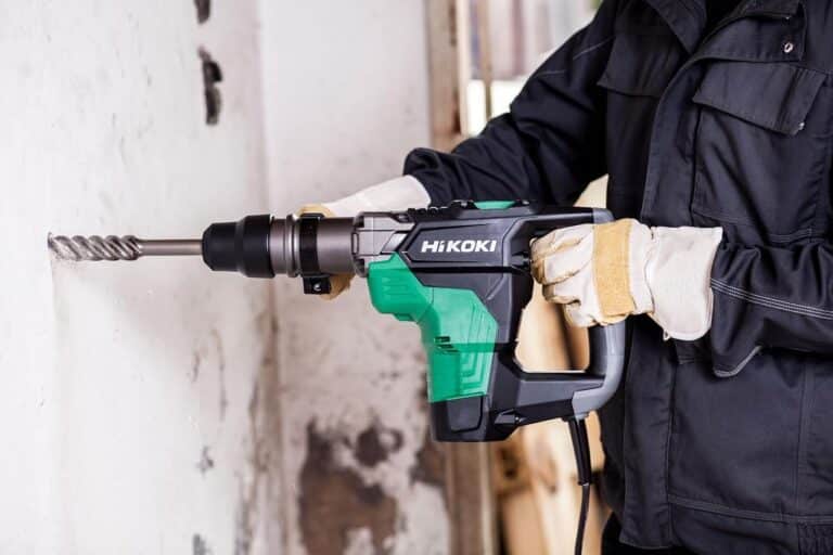 Un homme qui utilise un marteau de forage et de burinage de la marque HiKOKI sur un chantier.