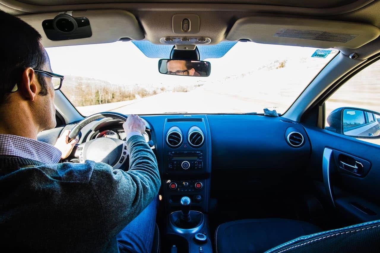 Un homme au volant qui utilise un kit mains libres.