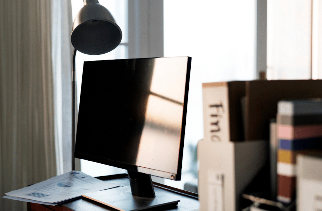 Un bureau avec une lampe et un PC fixe.