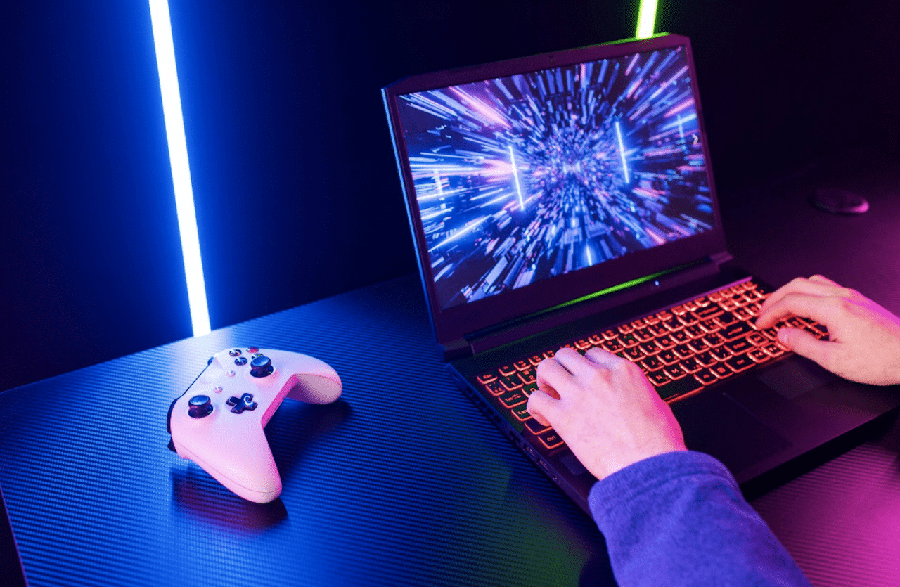 Une personne qui joue à un jeu vidéo sur un PC portable gamer dans un set up éclairé au néon.