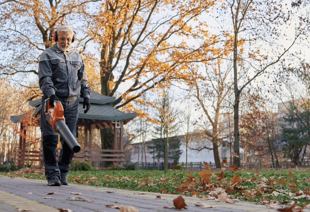 Un homme qui utilise un aspirateur souffleur dans un parc en automne.