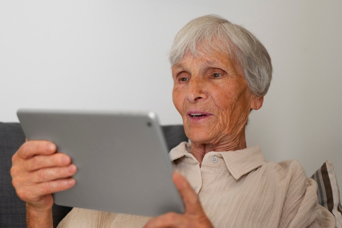 Une personne âgée utilisant une tablette tactile pour senior.