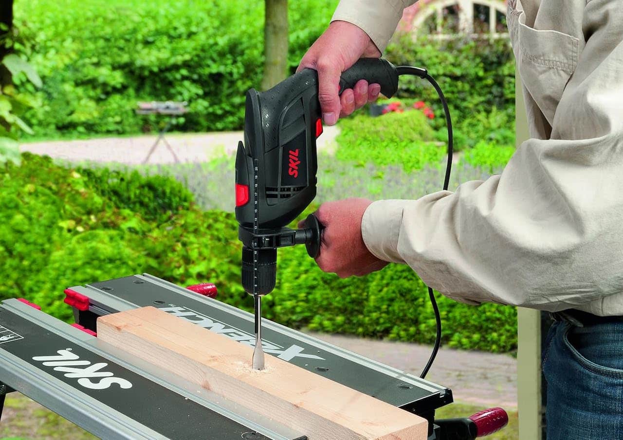 Un homme qui utilise une perceuse à percussion de la marque SKIL.