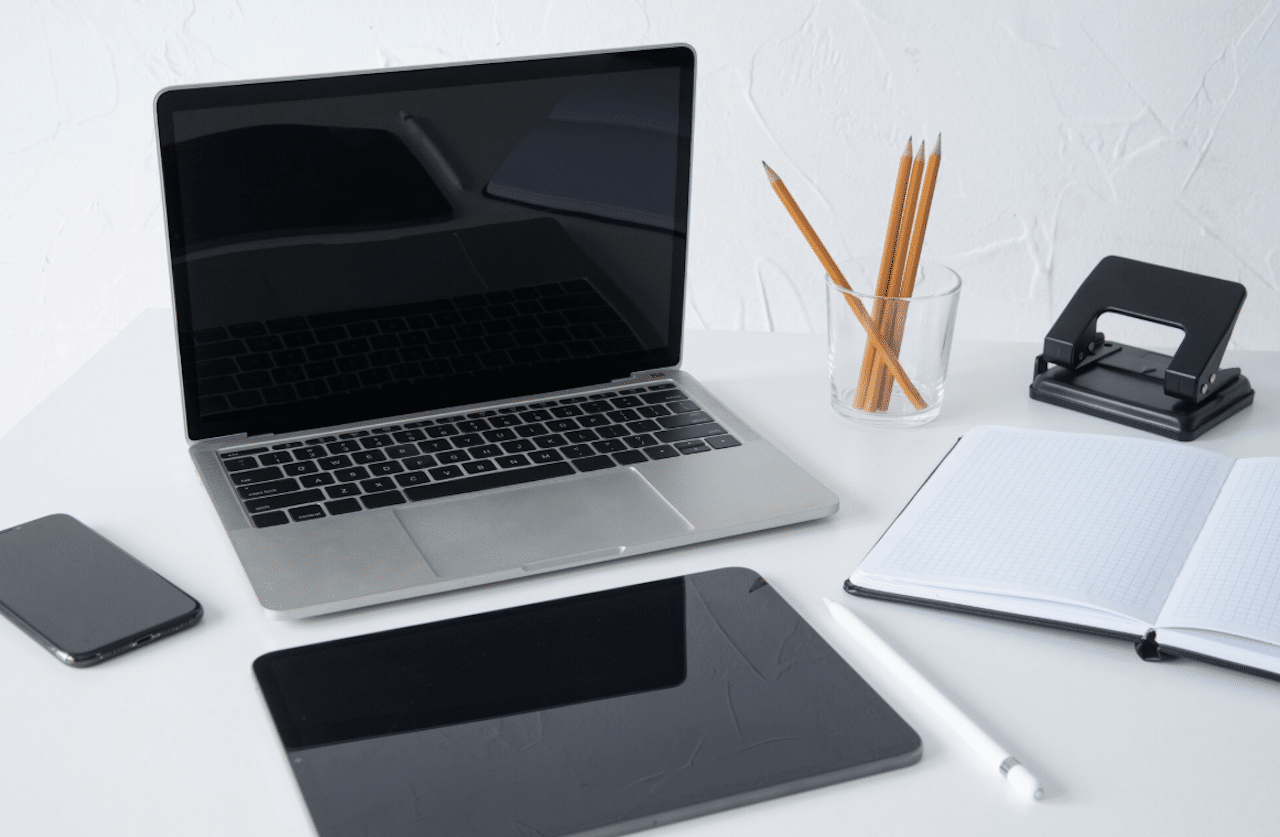 Un ordinateur portable accompagné d'une tablette tactile et d'un cahier.