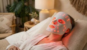 Une femme allongée avec un masque LED blanc sur le visage