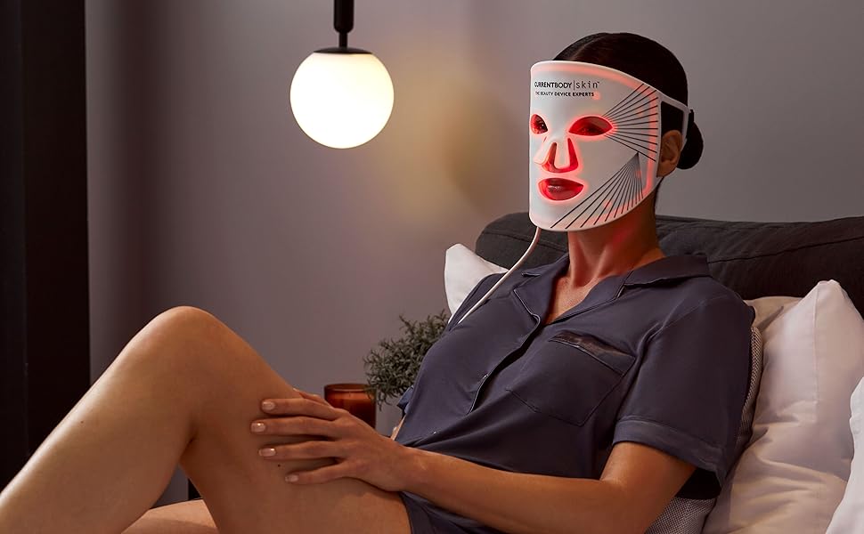 Une femme allongée portant un masque LED currentbody à lumière rouge