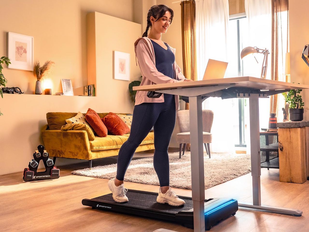 Une femme qui travail sur un bureau surélevé en même temps de marcher sur un tapis roulant.