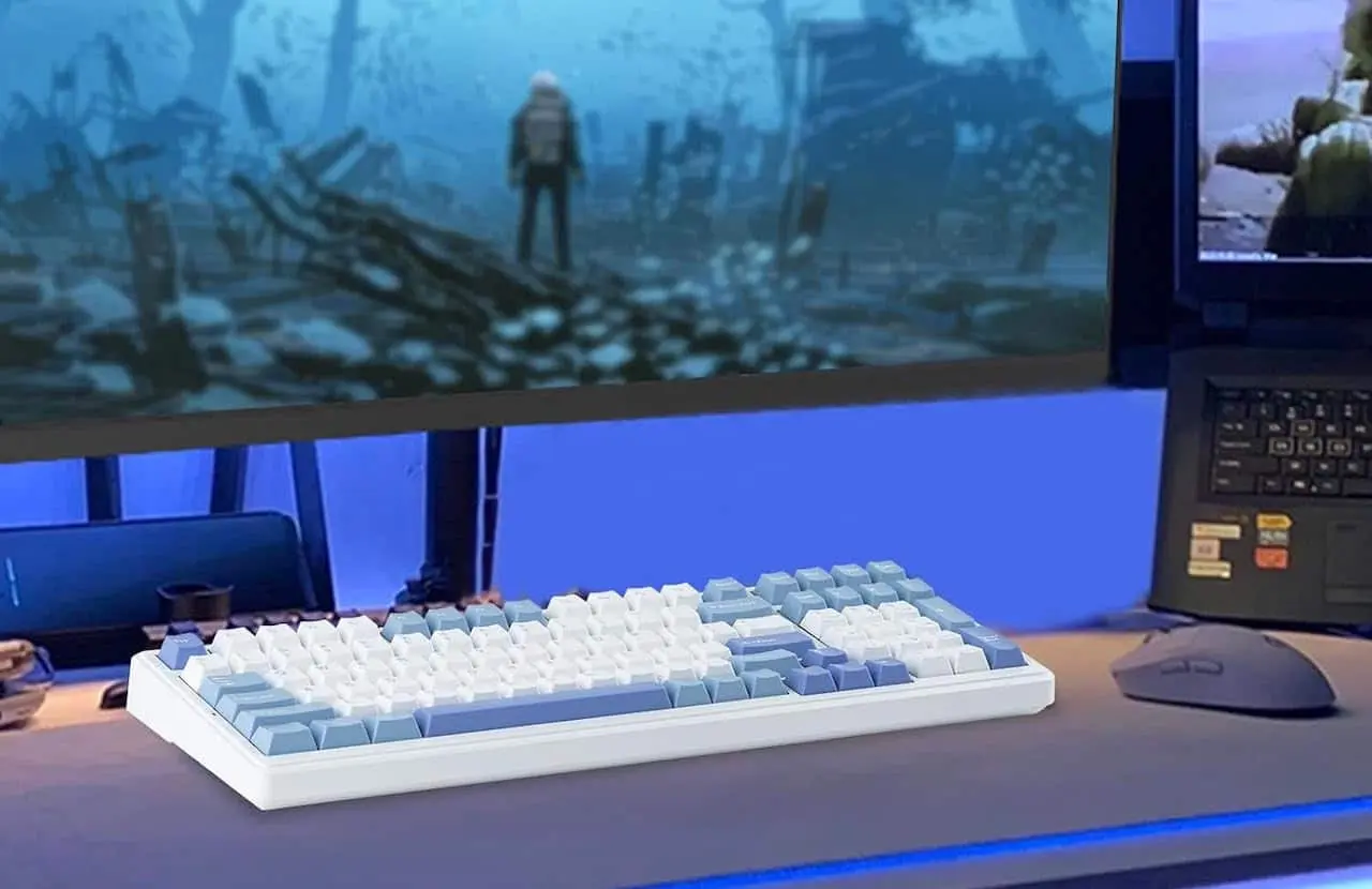 Un clavier mécanique blanc avec des touches blanches et bleues posé sur un bureau en bois