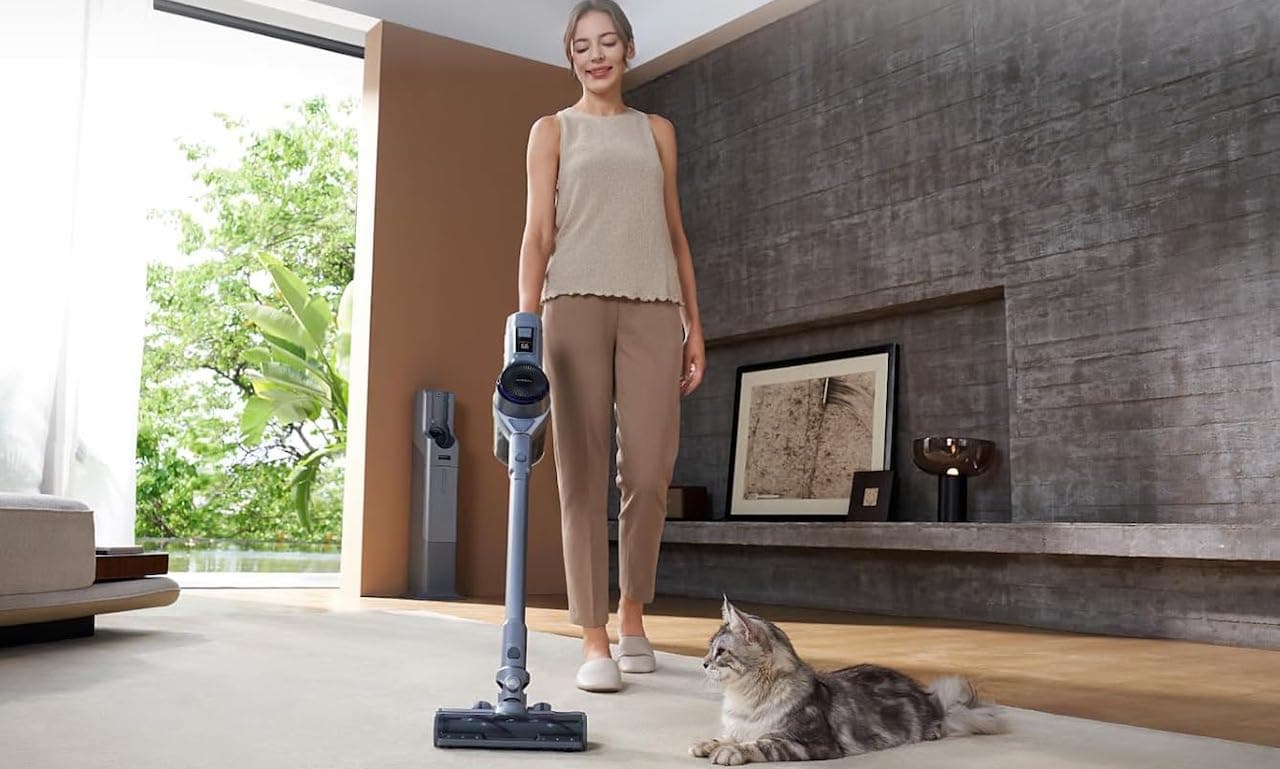 Une femme utilise un aspirateur balai laveur sans fil de la marque Narwal.