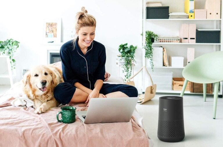 Une femme et son chien dans une chambre lumineuse avec un purificateur d'air Winix.