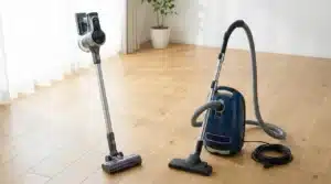 Un aspirateur balai à coté d'un aspirateur traineau dans une pièce avec un parquet en bois