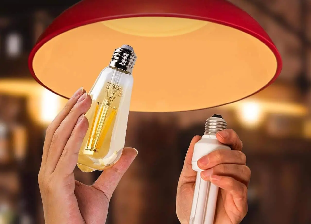 Une personne dont on ne voit que les mains remplace une ancienne ampoule fluo par une ampoule LED connectée