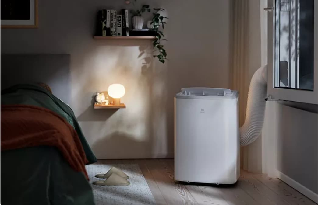 Un climatiseur mobile dans une chambre cocooning en soirée.
