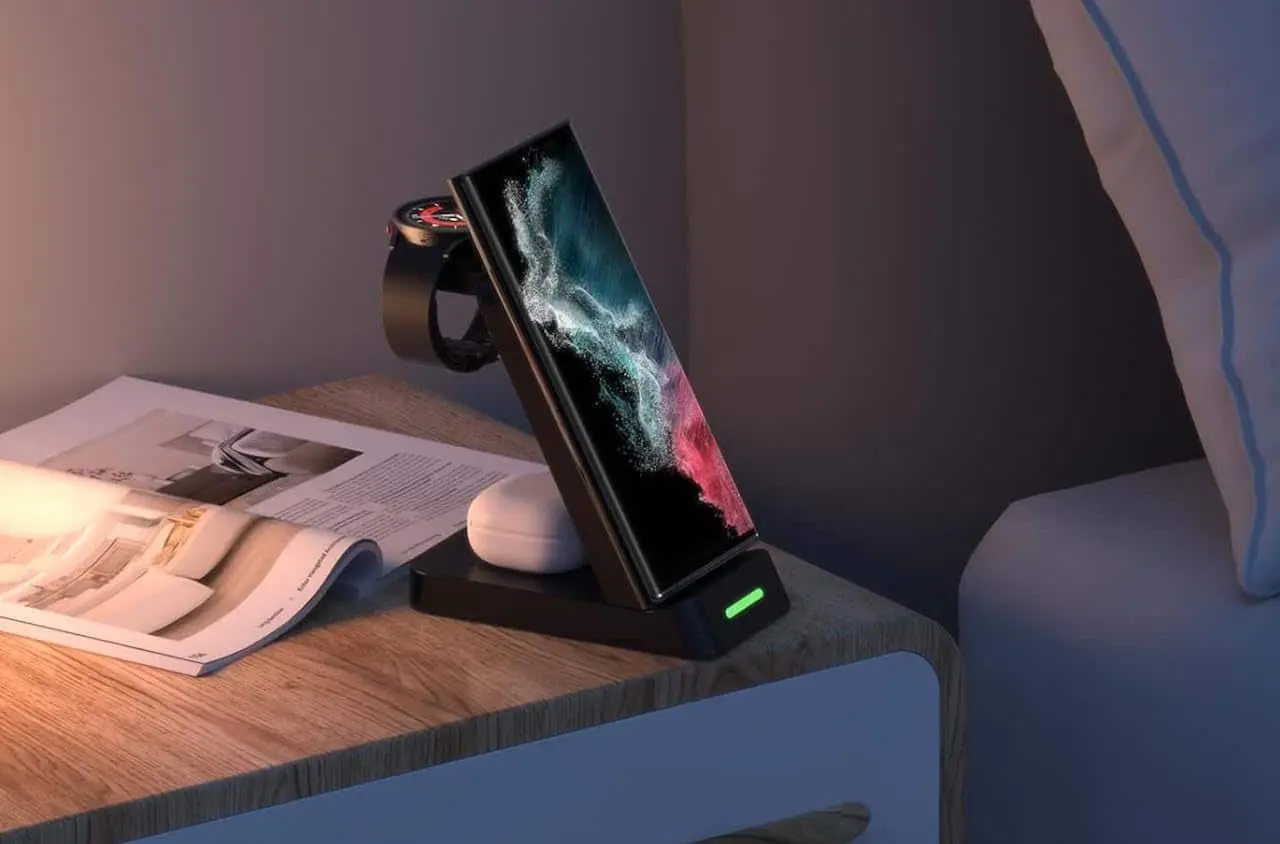Un smartphone en train de charger sur un chargeur à induction au format chevalet sur une table de nuit.