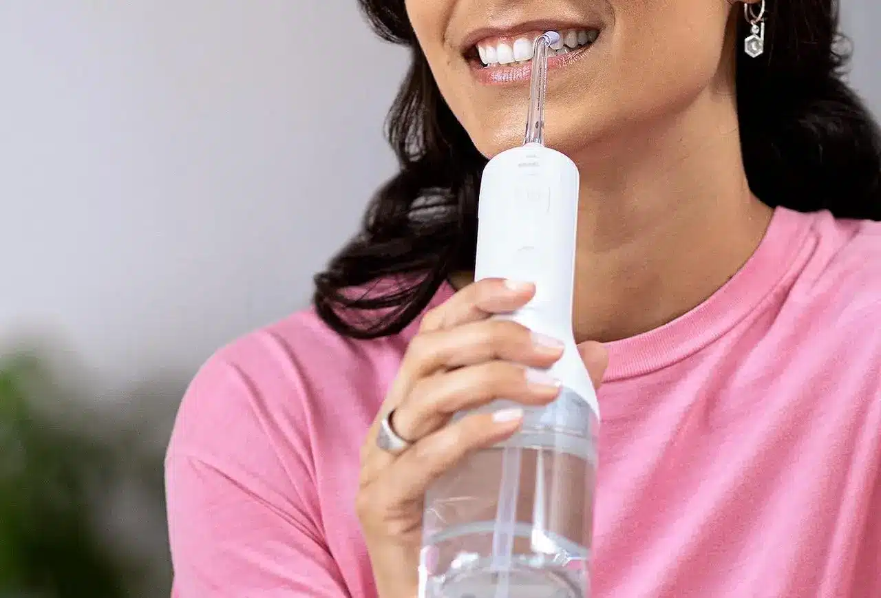 Une femme brune utilisant un hydropulseur dentaire