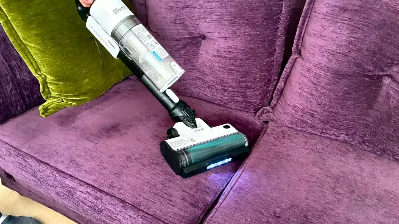 Utilisation de l'aspirateur balai Levoit Lvac 200 sur un canapé en tissu en mode aspirateur à main.