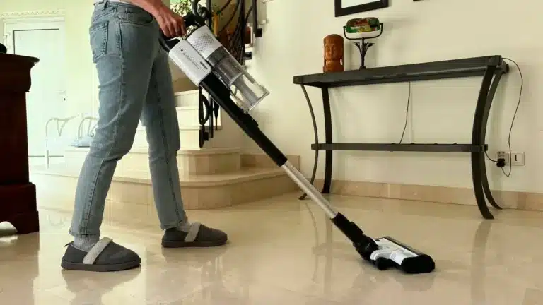 Une femme utilise l'aspirateur balai sans fil Levoit LVAC 200 sur un sol en marbre